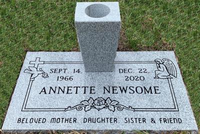 single gray granite headstone with dove, cross, and praying angel emblems